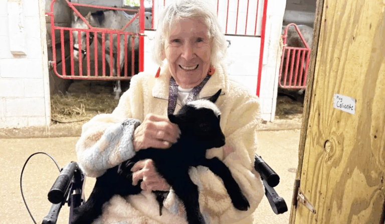 Grace Point Place Memory Care resident holds a baby goat at Memory Lane Stables