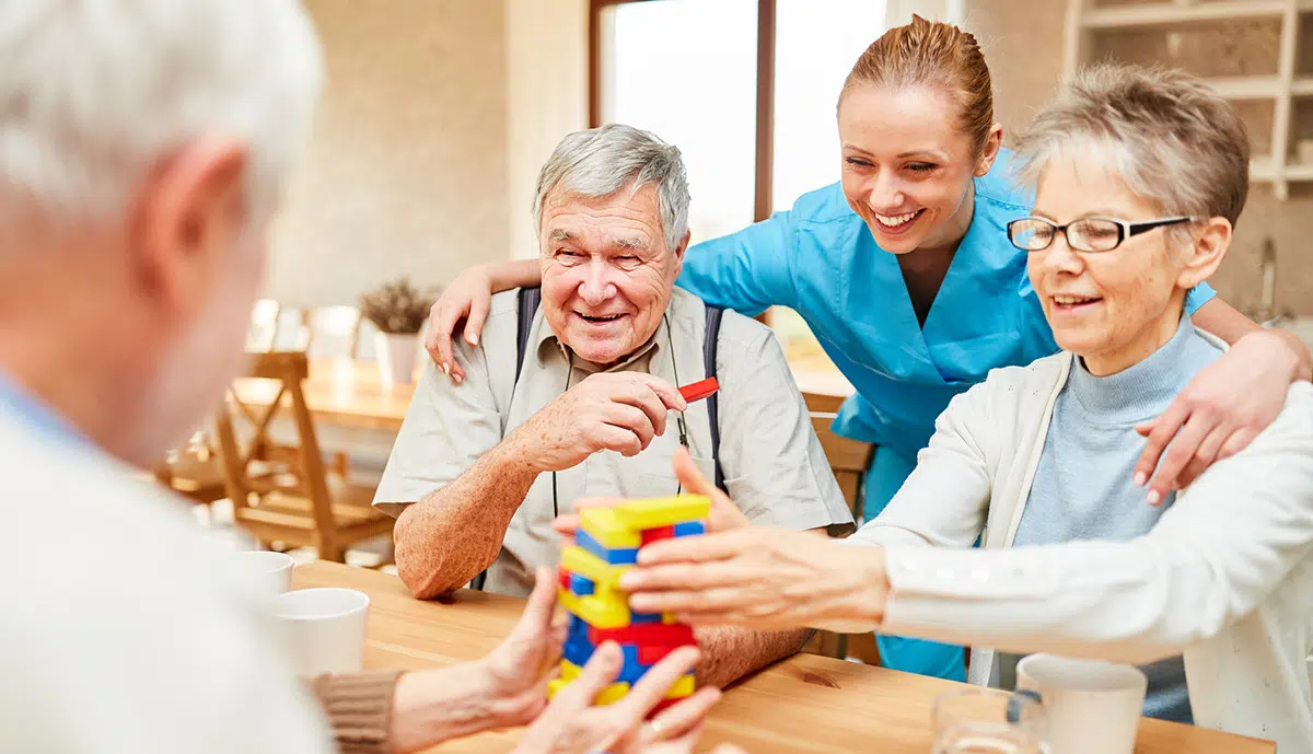 Life engagement director helps memory care residents with a puzzle